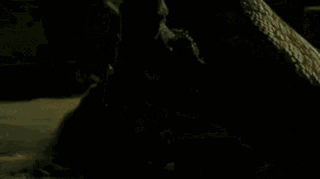 a woman is sitting on the ground in a dark room holding a skateboard .