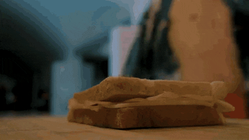a person is making a sandwich with peanut butter and cheese on a wooden table .