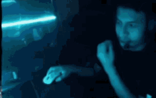 a person is standing in a dark room with a blue light behind them .