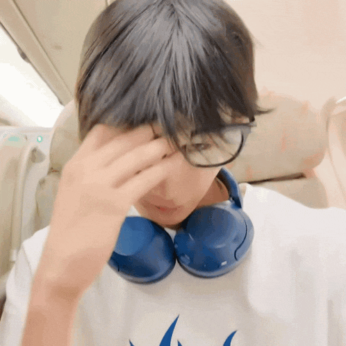 a young boy wearing glasses and headphones holds his head