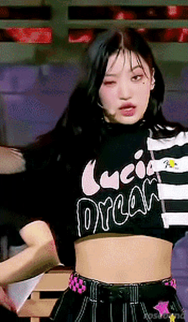 a girl is wearing a black and white striped crop top with the word dream on it .