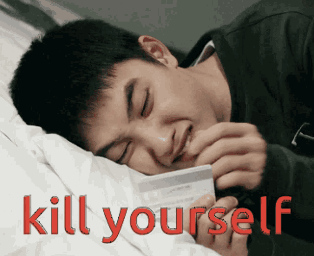 a man is laying on a bed holding a credit card with the words kill yourself written on the bottom