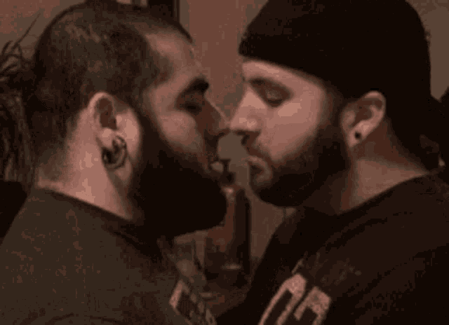 two men with beards are kissing each other in front of a mirror