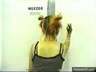 a woman stands in front of a sign that says weezer on it