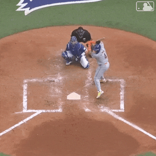 a baseball player is swinging a bat at a ball while a catcher watches .