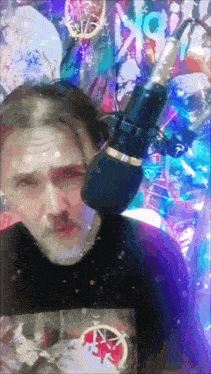a man is singing into a microphone in front of a painting
