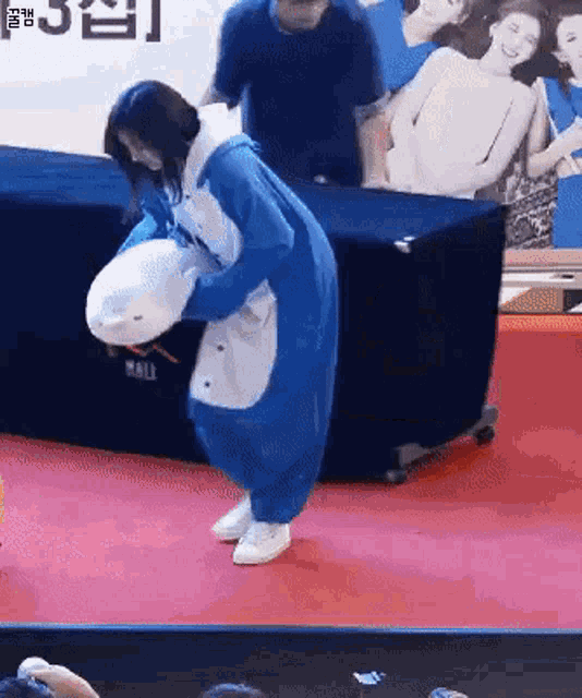 a woman in a blue and white shark costume is holding a stuffed animal