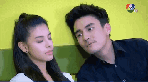 a man and a woman are looking at each other in front of a yellow wall ..