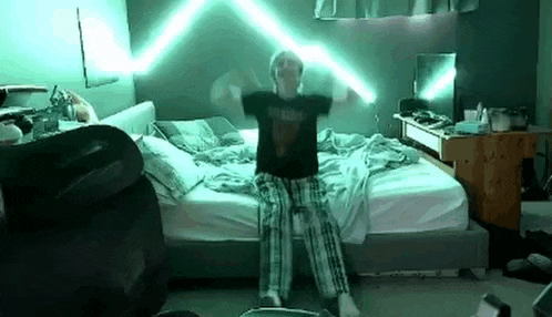 a man is sitting on a bed with his arms outstretched and a green light coming out of his head .
