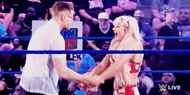 a man and a woman are shaking hands in a wrestling ring with a w live logo on the bottom