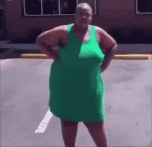 a woman in a green dress is standing in a parking lot .