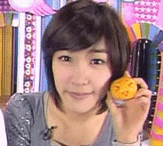 a young woman is holding a small yellow object in her hand