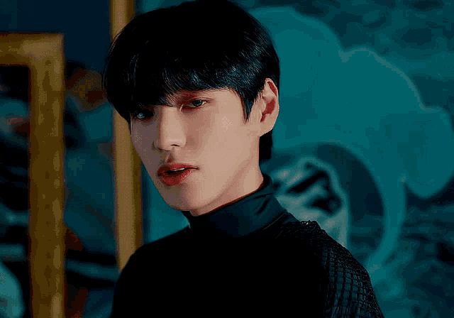 a close up of a young man 's face in front of a blue wall