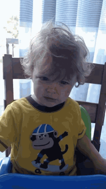 a young boy wearing a yellow shirt with a picture of a monkey on it