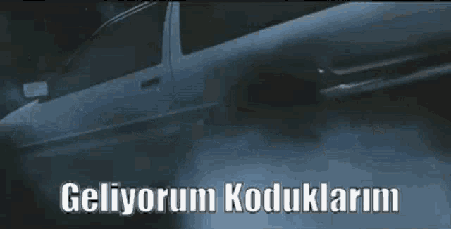 a white car is driving down a dark road with the words geliyorum koduklarim written on the bottom .
