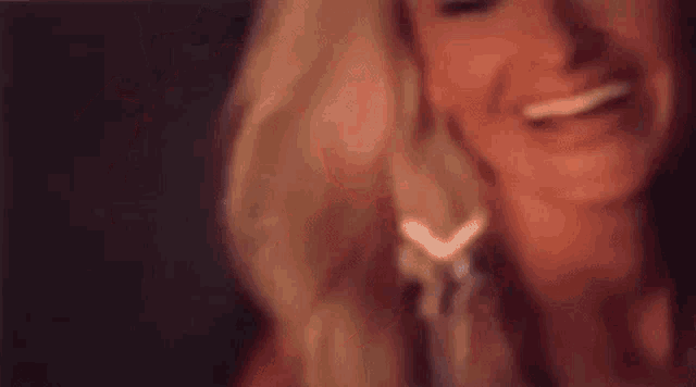 a close up of a woman 's face with her mouth open and earrings in her mouth .