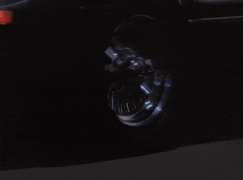 a car is driving down a dark street at night