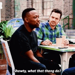 two men are sitting at a table with shawty what that thang do