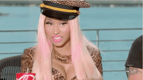 a woman with pink hair wearing a leopard print top and hat