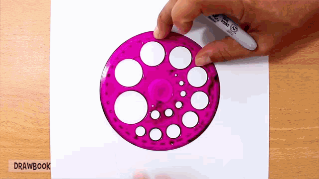 a person is drawing circles on a piece of paper with a pen that says drawbook
