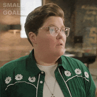 a woman wearing glasses and a green shirt with flowers on it