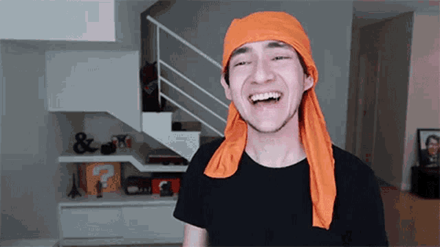 a man wearing an orange headband is laughing in front of stairs