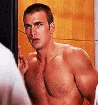 a shirtless man is standing in front of a mirror and pointing up .