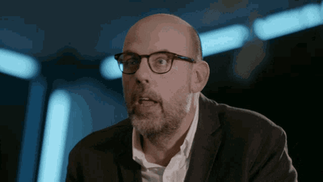 a bald man with glasses and a beard is making a funny face