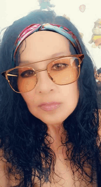 a woman wearing sunglasses and a headband takes a selfie