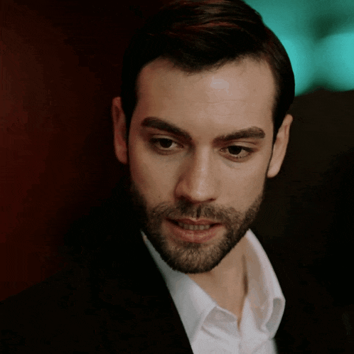 a man with a beard is wearing a suit and a white shirt