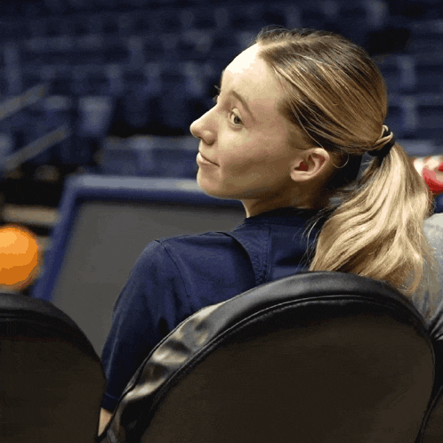 a woman with a ponytail sits in a chair