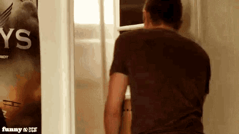 a man is standing in front of a refrigerator with a poster on the wall that says sky 's .
