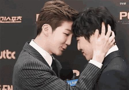a man in a suit is touching another man 's face .