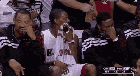 a man in a miami jersey is sitting in the stands during a basketball game