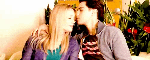 a man is kissing a woman on the forehead while they are sitting on a couch .