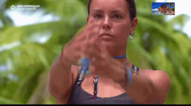 a woman wearing an under armour tank top is making a stop sign with her hands