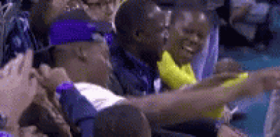 a group of people are sitting in a stadium holding hands and laughing .