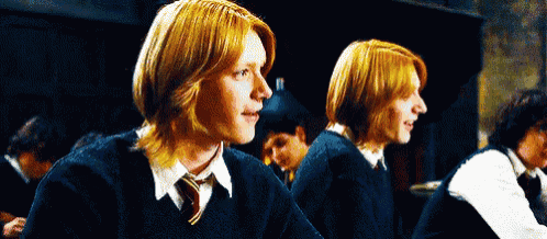 two red haired boys in school uniforms are sitting next to each other in a dark room .