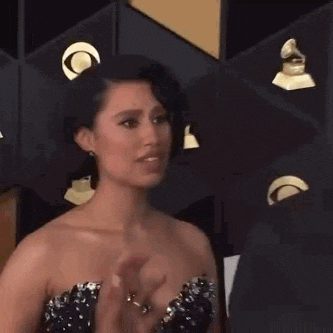 a woman in a strapless dress is smiling at the camera while standing on a red carpet .