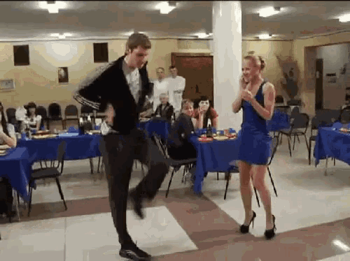a man and a woman are dancing in front of tables and chairs