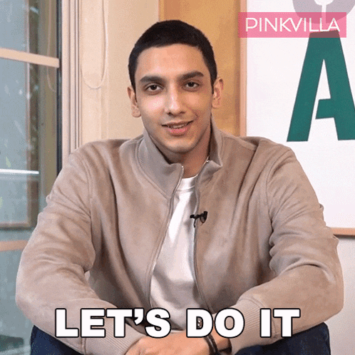 a man is sitting in front of a pinkvilla sign