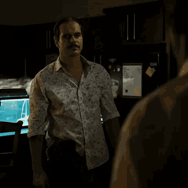 a man with a mustache is standing in front of a refrigerator with a note on it
