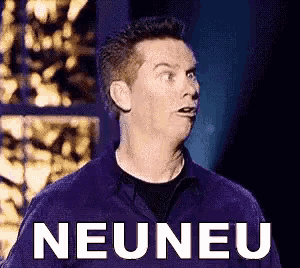 a man in a purple shirt is standing in front of a sign that says neuneu .