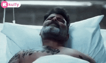 a man is laying in a hospital bed with a tattoo on his chest .