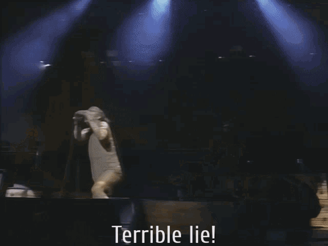 a man singing into a microphone on stage with the words terrible lie below him