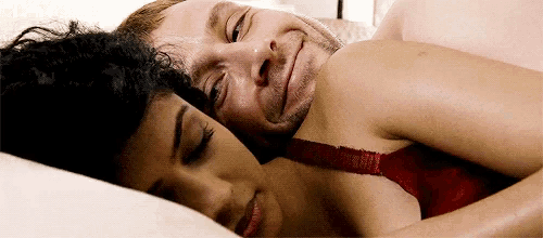 a man and a woman are laying in bed and hugging each other .