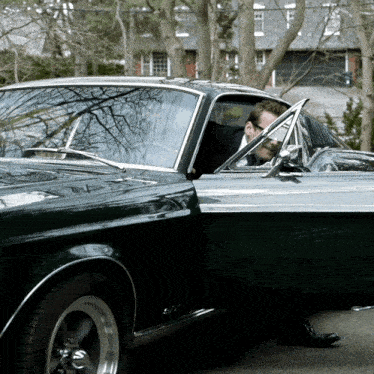 a man is getting out of a black car