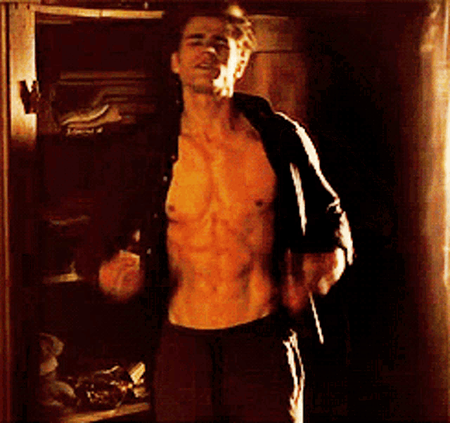 a shirtless man stands in front of a closet