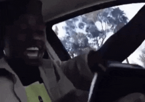 a man is driving a car while holding a cell phone .