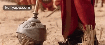 a man in a red robe is standing next to a giant hammer in the dirt .
